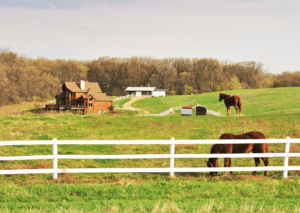 A picturesque farm scene with a wooden house highlights the importance of comprehensive farm insurance and ranch insurance.
