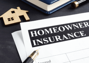 An insurance document on a desk with a house model, pen, and book in the background, emphasizing coverage and protection.