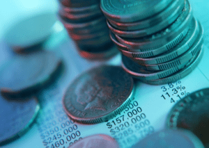 Close-up of stacked coins and financial figures on a document, symbolizing savings, investment, and financial planning.