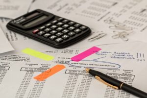 Calculator, pen, and financial documents, representing Business Insurance Fort Collins planning and risk assessment.