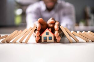 A miniature house from falling dominoes, representing Home Insurance Greeley CO safeguarding homes from cascading risks.