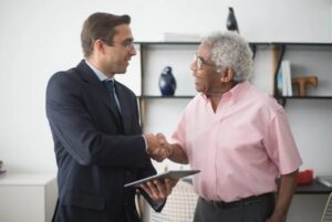 Two men shaking hands in an office, one holding a tablet.