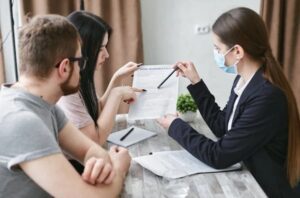 The insurance agent discusses policy details with a couple at a table during a meeting.